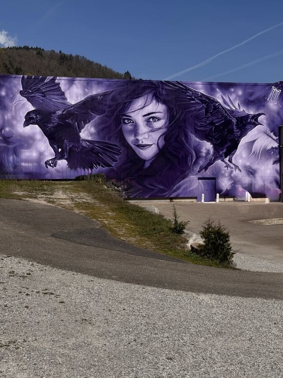 Fresque de street art 2025 à Aurec-sur-Loire signée Aéro représentant une jeune femme et des corbeaux