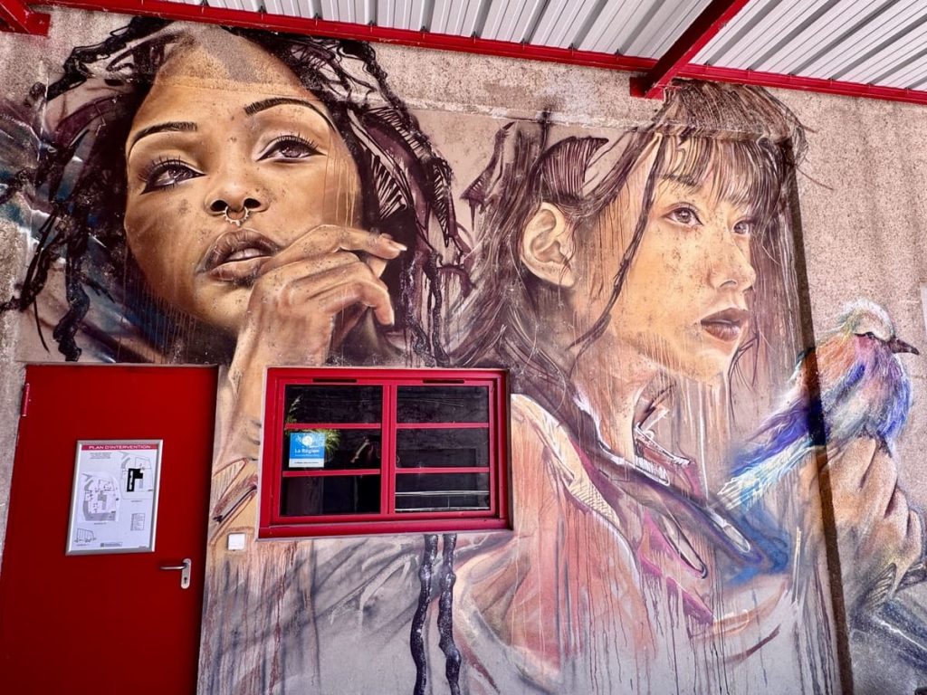 Œuvre de street art à Aurec-sur-Loire par Ifolapé représentant 2 jeunes femmes et un oiseau coloré