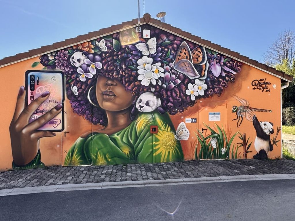 Fresque de street art à Aurec-sur-Loire représentant une jeunne femme à la chevelure exubérante avec fleurs, pandas et papillons